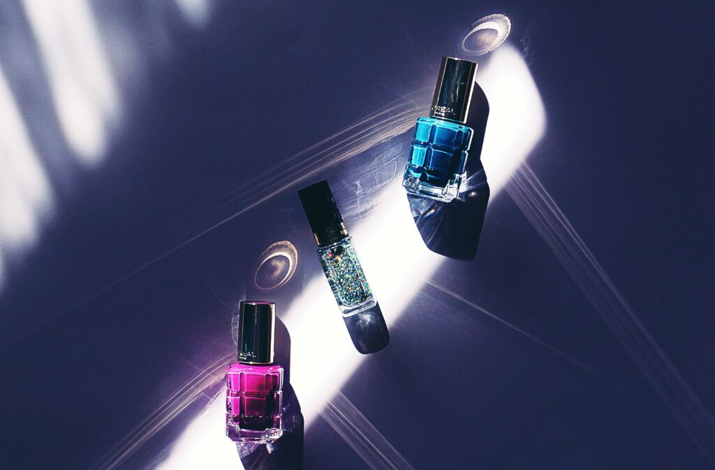 A close-up view of colorful nail polish bottles on a dark surface with striking light patterns.