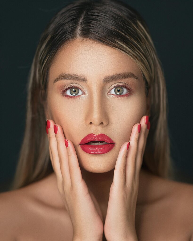Close-up portrait of a woman showcasing red lips and nails, emphasizing beauty and elegance.